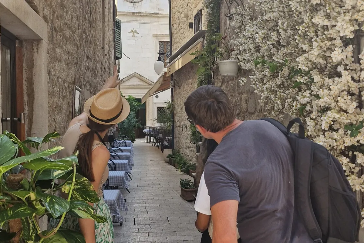 Ivana showing a guest a lane with café tables during the history and coffee tour of Šibenik