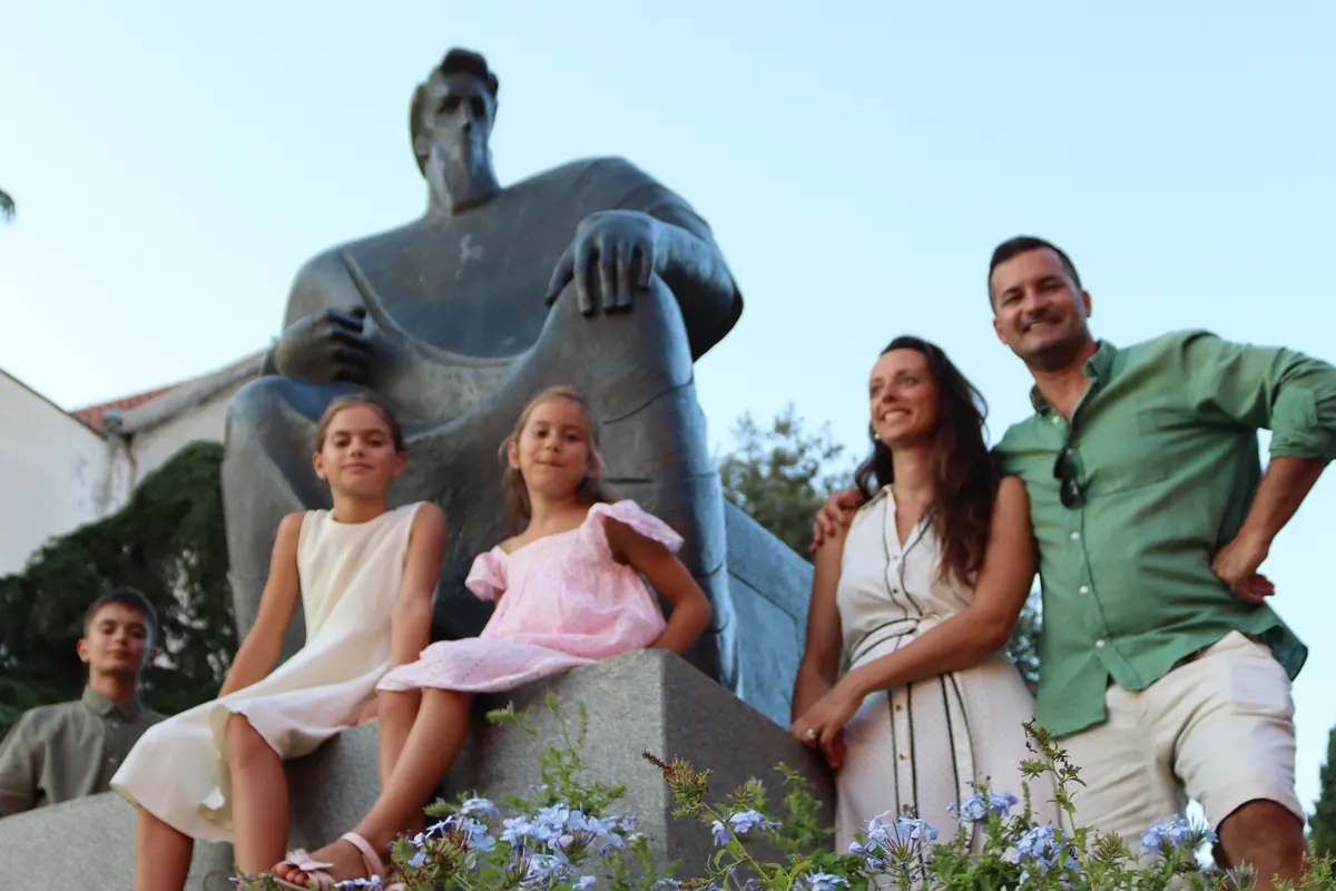 A family beside a stone monument in Šibenik at the end of their family walking tour
