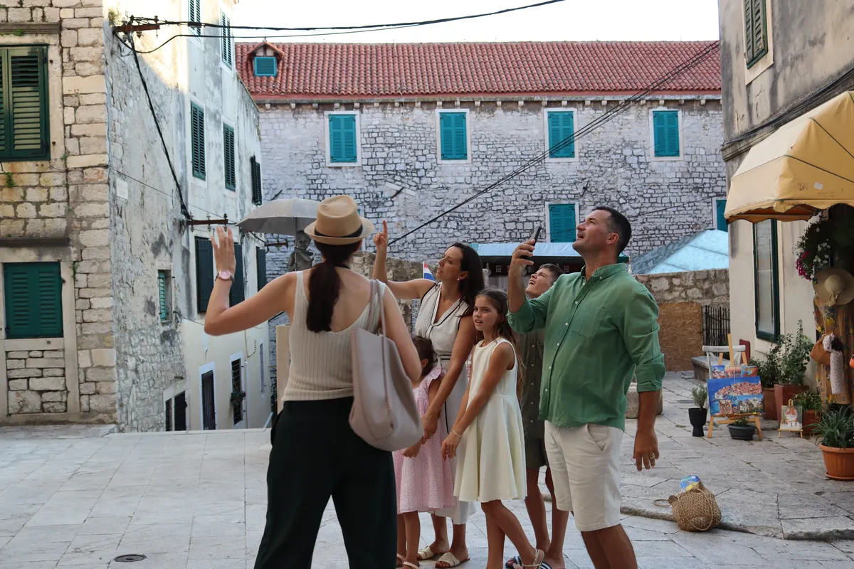 Ivana high-fiving children on a square during a family walking tour in Šibenik