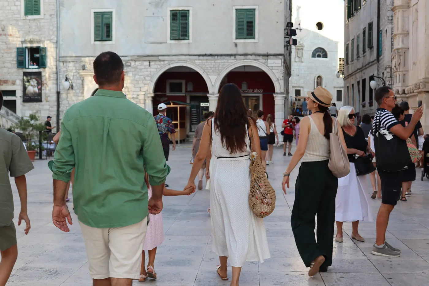 A family walking hand in hand across a square on a Šibenik family walking tour
