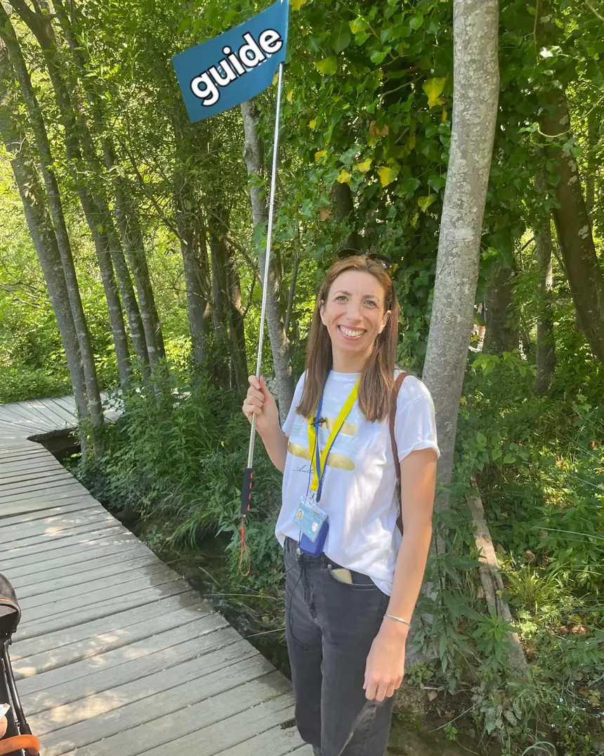 Ivana, licensed local guide, holding a guide sign on a boardwalk in Krka National Park