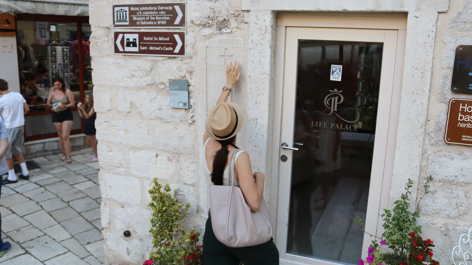 Ivana touching a carved stone inscription on a private Šibenik Old Town walking tour