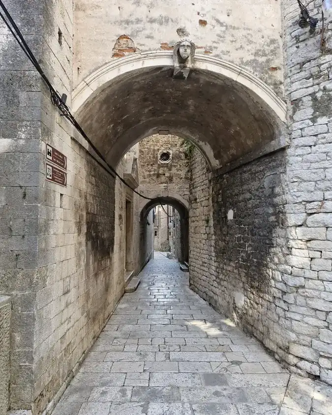 Stone archways over an empty lane in Šibenik's Old Town, on the route of the Homeland War walking tour