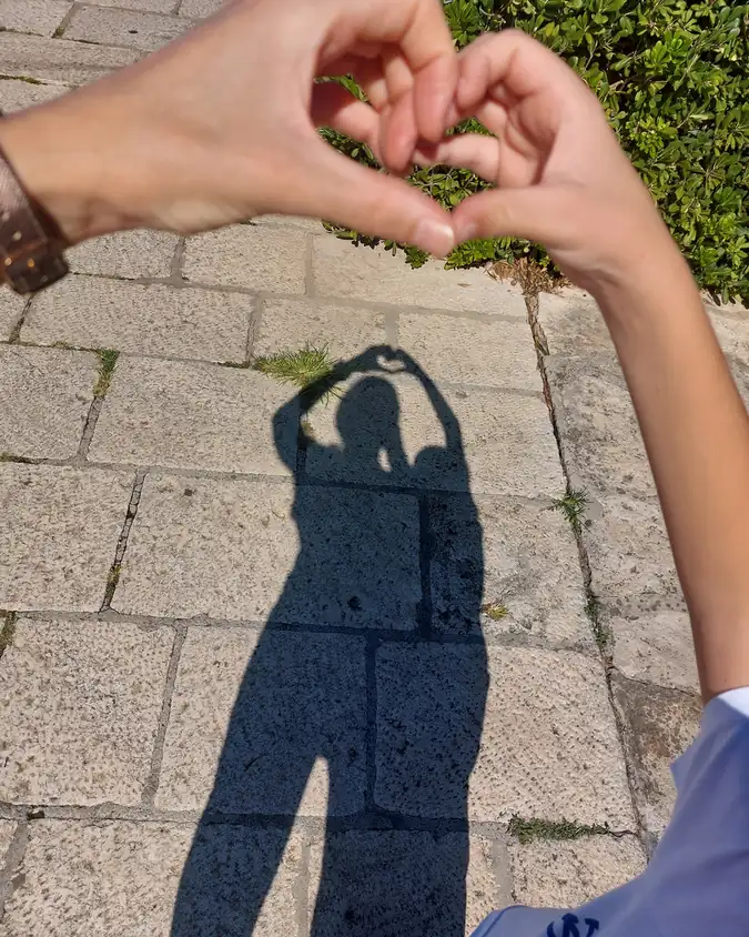 The shadow of hands forming a heart on Šibenik's stone pavement