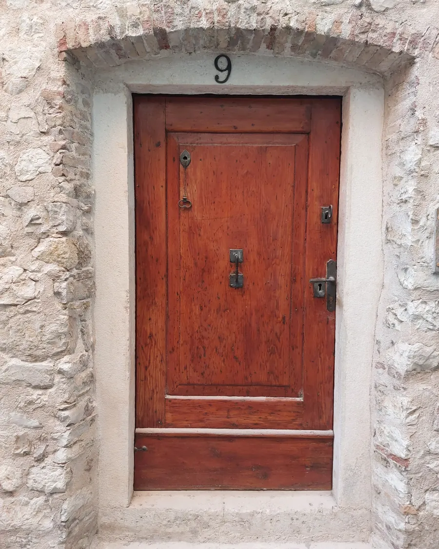 An old red wooden door in a stone wall in Šibenik's Old Town
