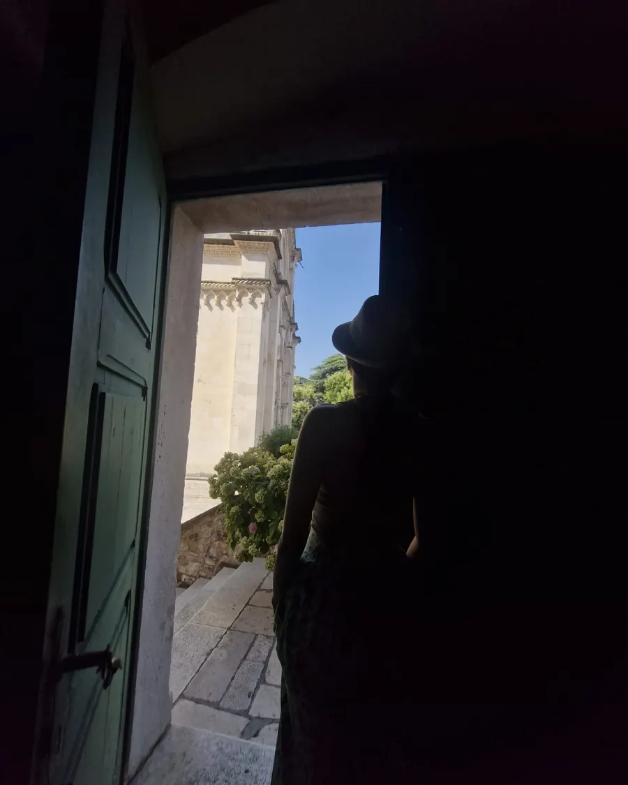 A silhouetted figure in a dark doorway looking out over Šibenik, an image from the Homeland War tour