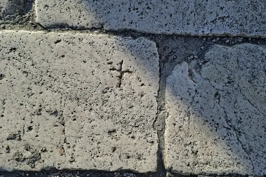 Pitted stone wall with a small carved cross in Šibenik, a quiet trace of the city's history